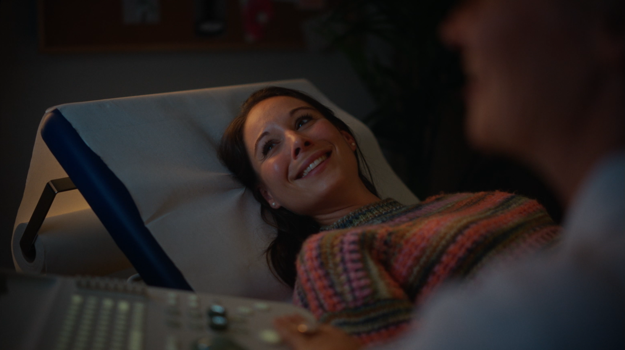A pregnant woman smiling while looking at an ultrasound machine monitor